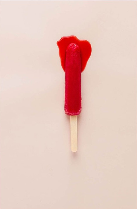 A melting red popsicle on a pink background